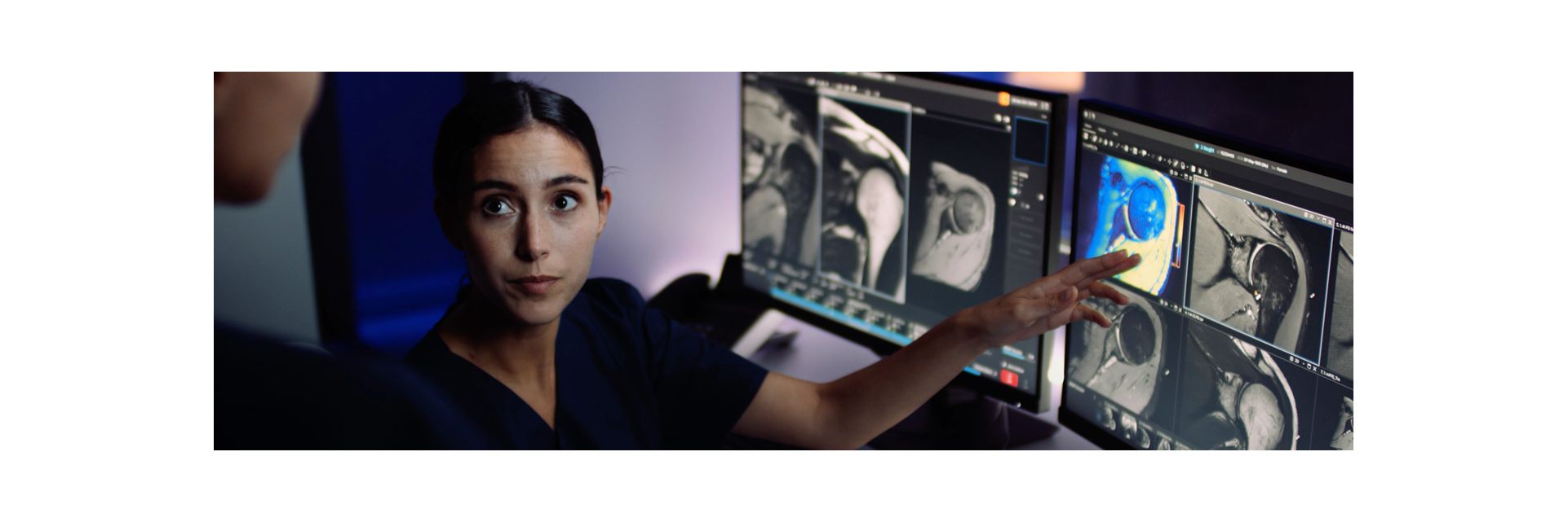 Technologist sitting behind MR console reviewing images