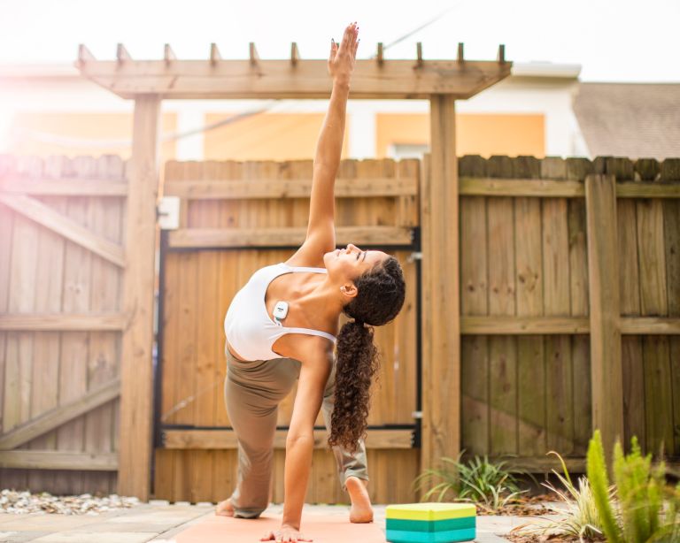 A woman stays active doing yoga while wearing a cardiac ambulatory monitoring device.