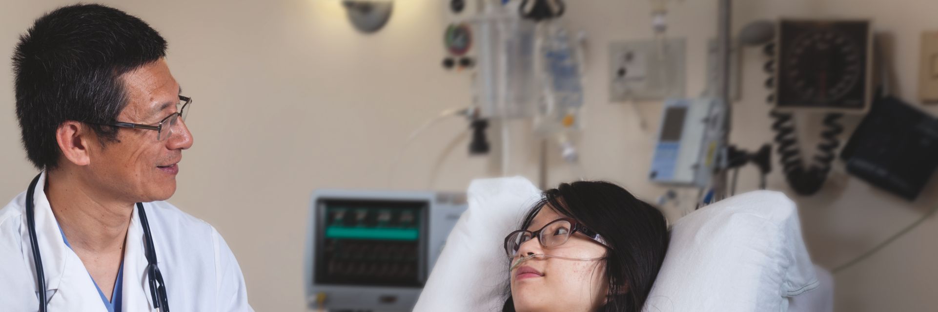 Image of a clinician interacting with a patient who is lying in a hospital bed.