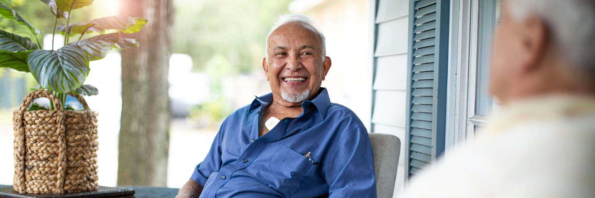 A man sits on his front porch at home while being monitored with a Philips Cardiac Ambulatory Monitoring device