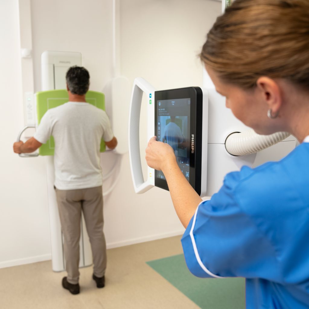 Radiography 7300 C and patient in examination room whilst radiographer operates system