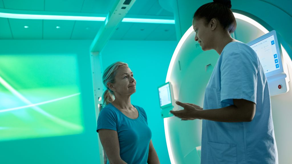Technician discussing MR procedure with patient while preparing for scan