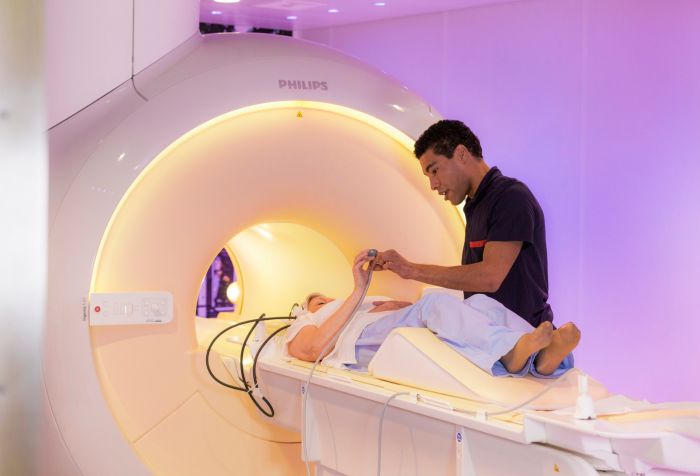 MRI laborant helping patient on exam bed