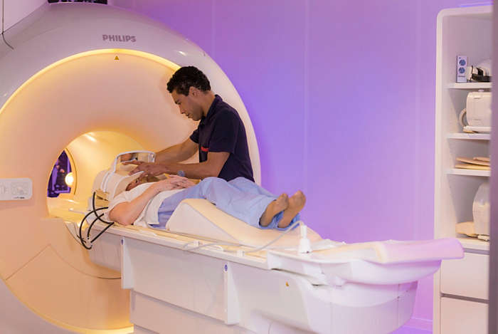 MRI laborant helping patient on exam bed