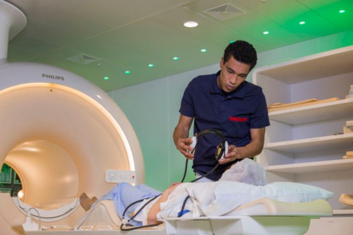 MRI laborant helping patient on exam bed