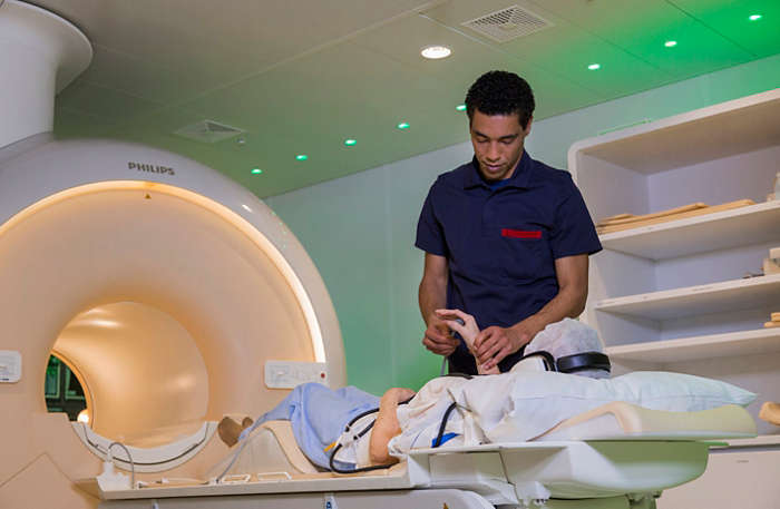 MRI laborant helping patient on exam bed