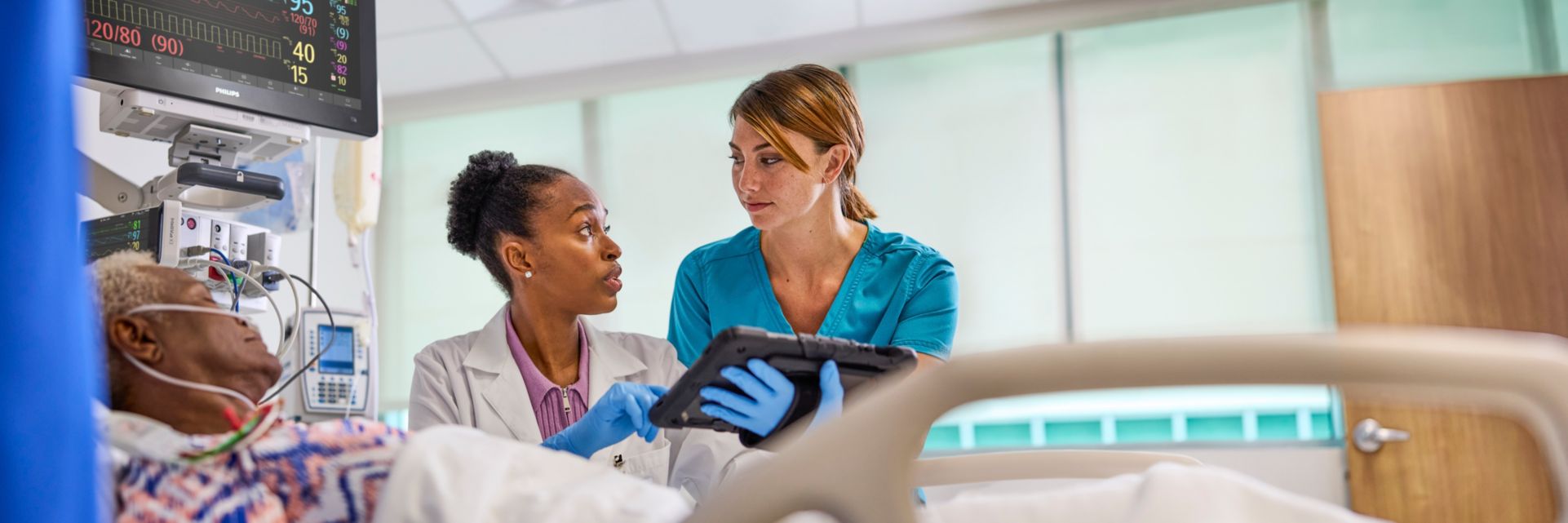 Nurse, doctor at bedside with tablet