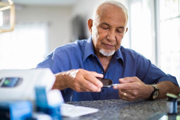 A man takes a blood glucose reading at home