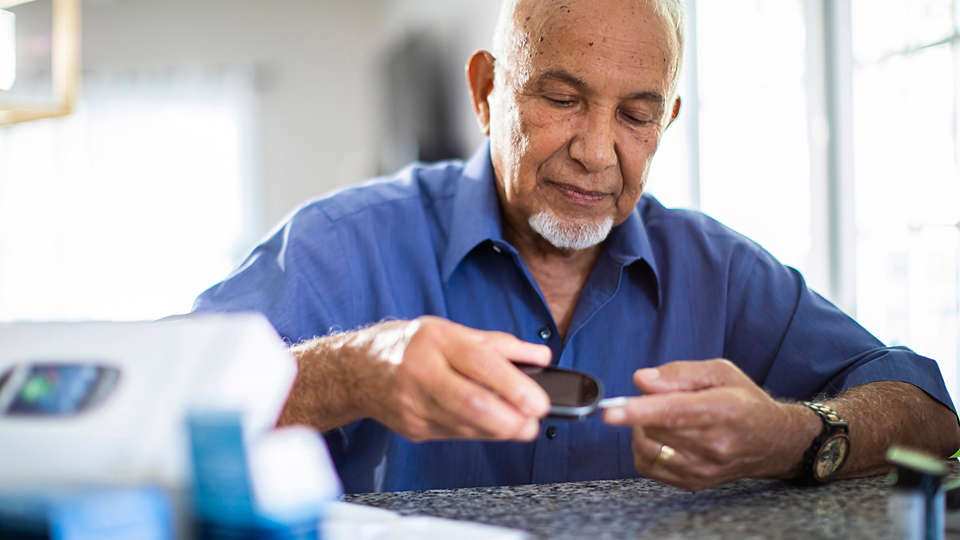 A man takes a blood glucose reading at home