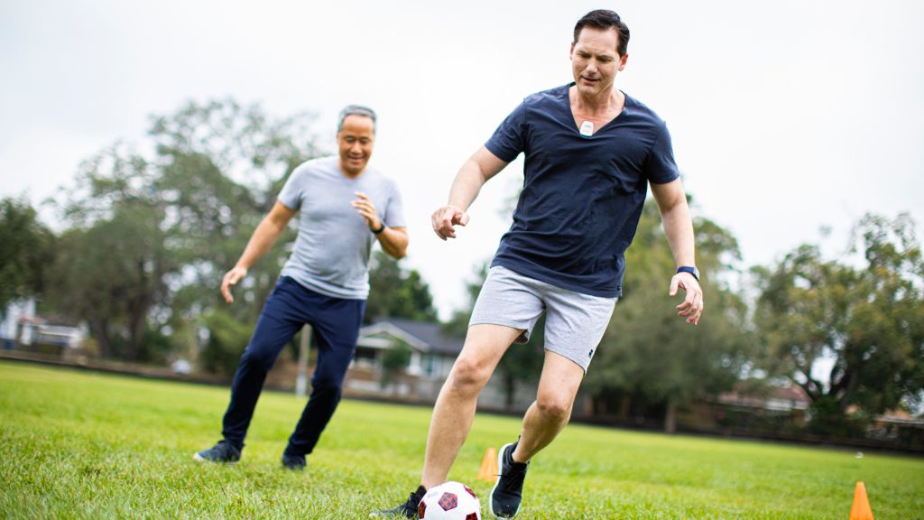 A man plays soccer while wearing a Philips Cardiac Ambulatory Monitoring device.