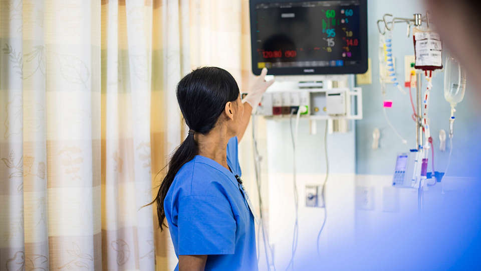 An acute care nurse turns off a bedside alarm