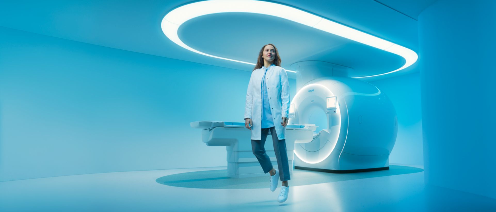 radiology tech in front of a helium free MRI machine