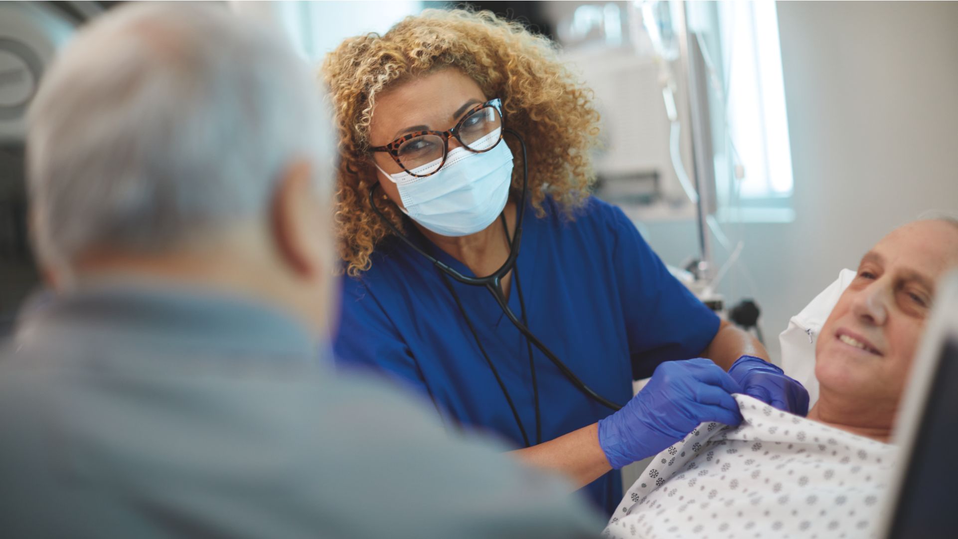 Pflegende versorgt einen Patienten im Bett
