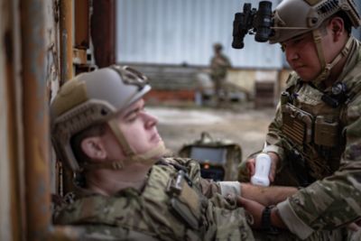 Military medic using point-of-care ultrasound on injured soldier