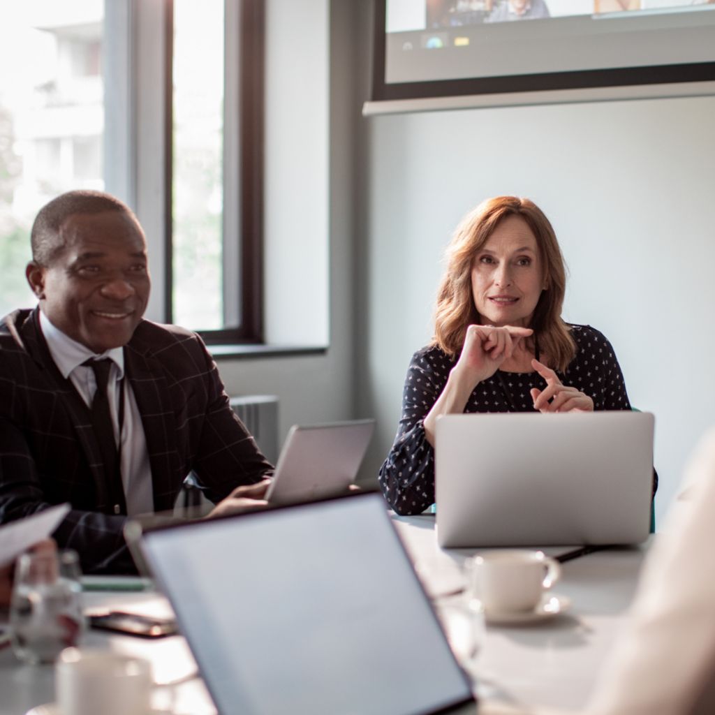 Executives sitting round a table with laptops