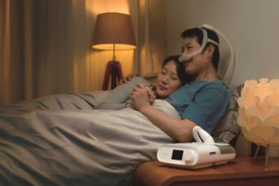 一位男性佩戴飞利浦睡眠呼吸机与伴侣依偎入睡