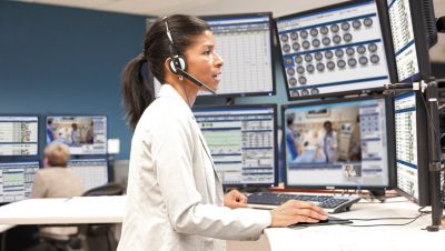 Clinician in a command center monitoring patients remotely on multiple screens