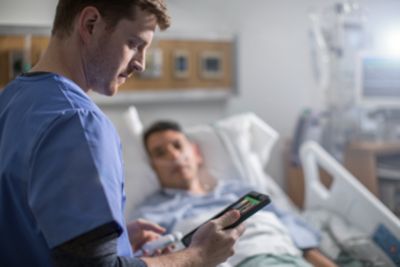 Clinician using Lumify on tablet at bedside with patient in hospital room