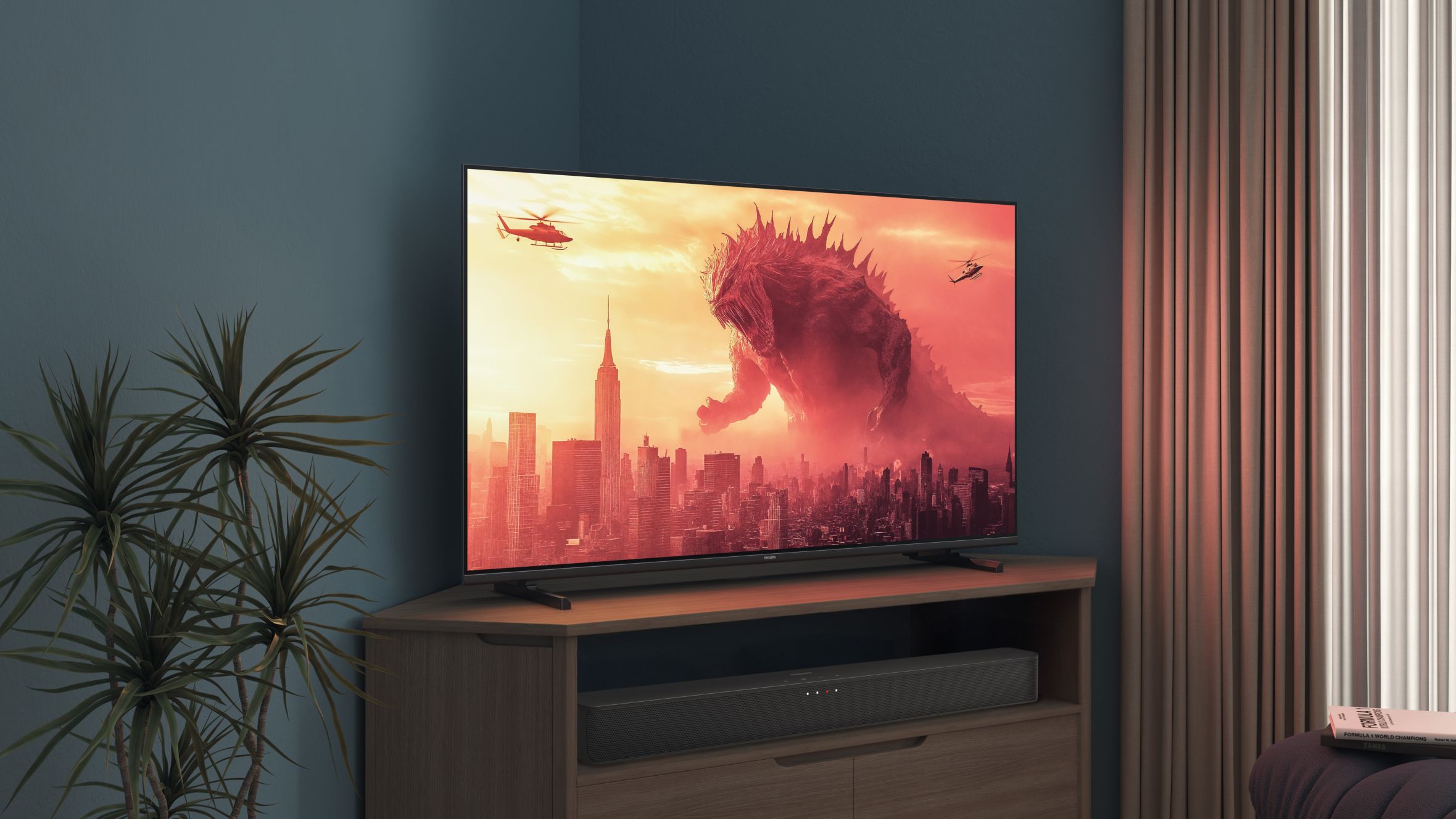 A Philips TV on a corner stand displays a Godzilla movie
