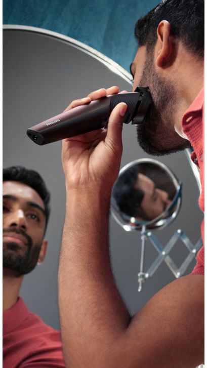 Mann som barberer skjegget sitt foran speilet
