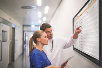 Doctor and nurse reviewing patient data on digital hospital display