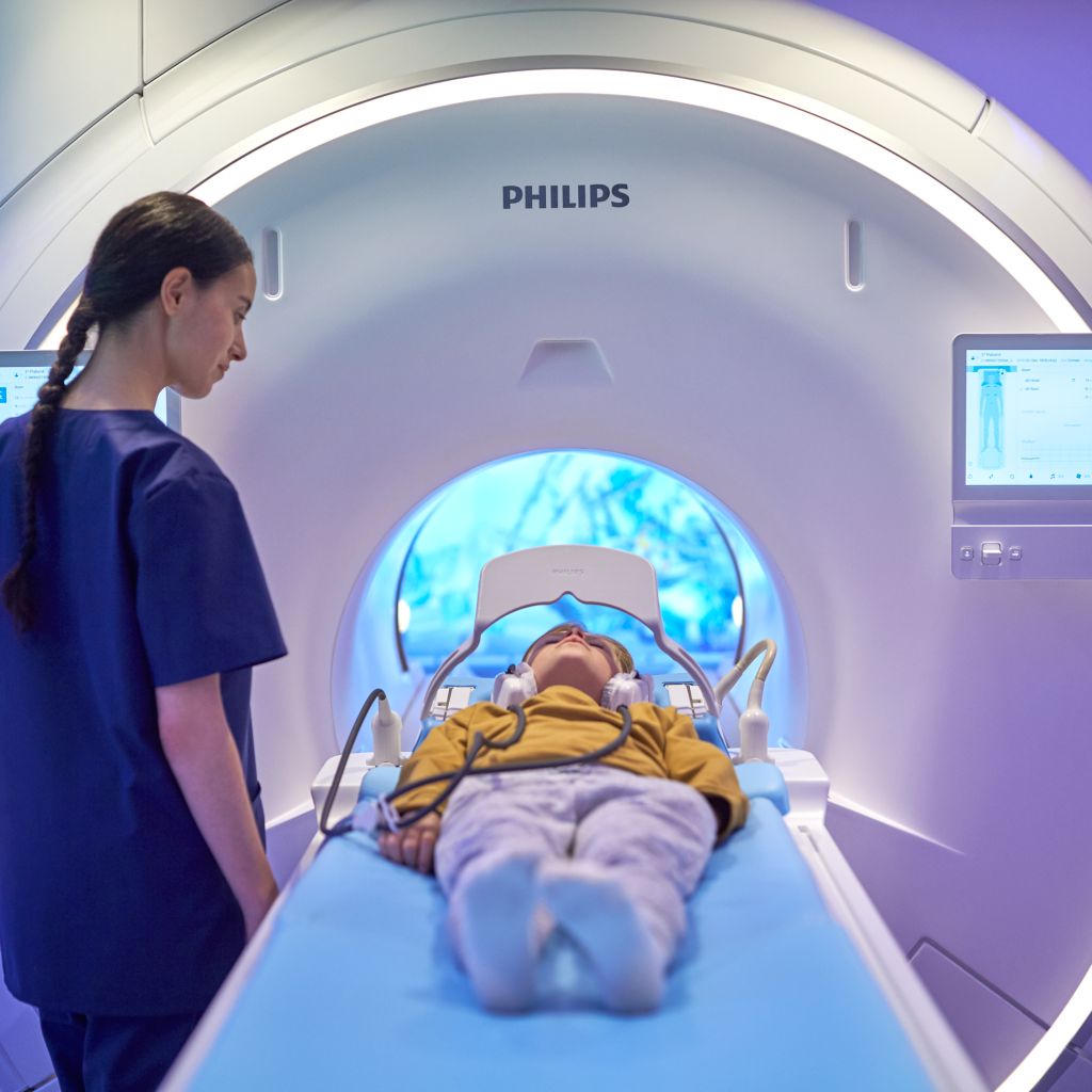 technologist moving pedatric patient into the mr scanner while the patient is watching a screen via the ambient experience mirror