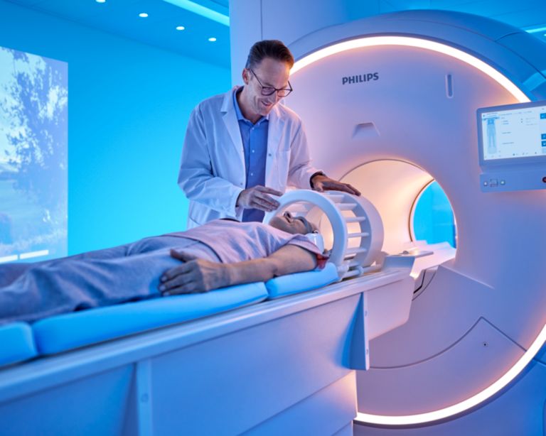 Researcher positioning the head coil on the patient for a brain exam with the Philips Ambient Experience in the MRI room.