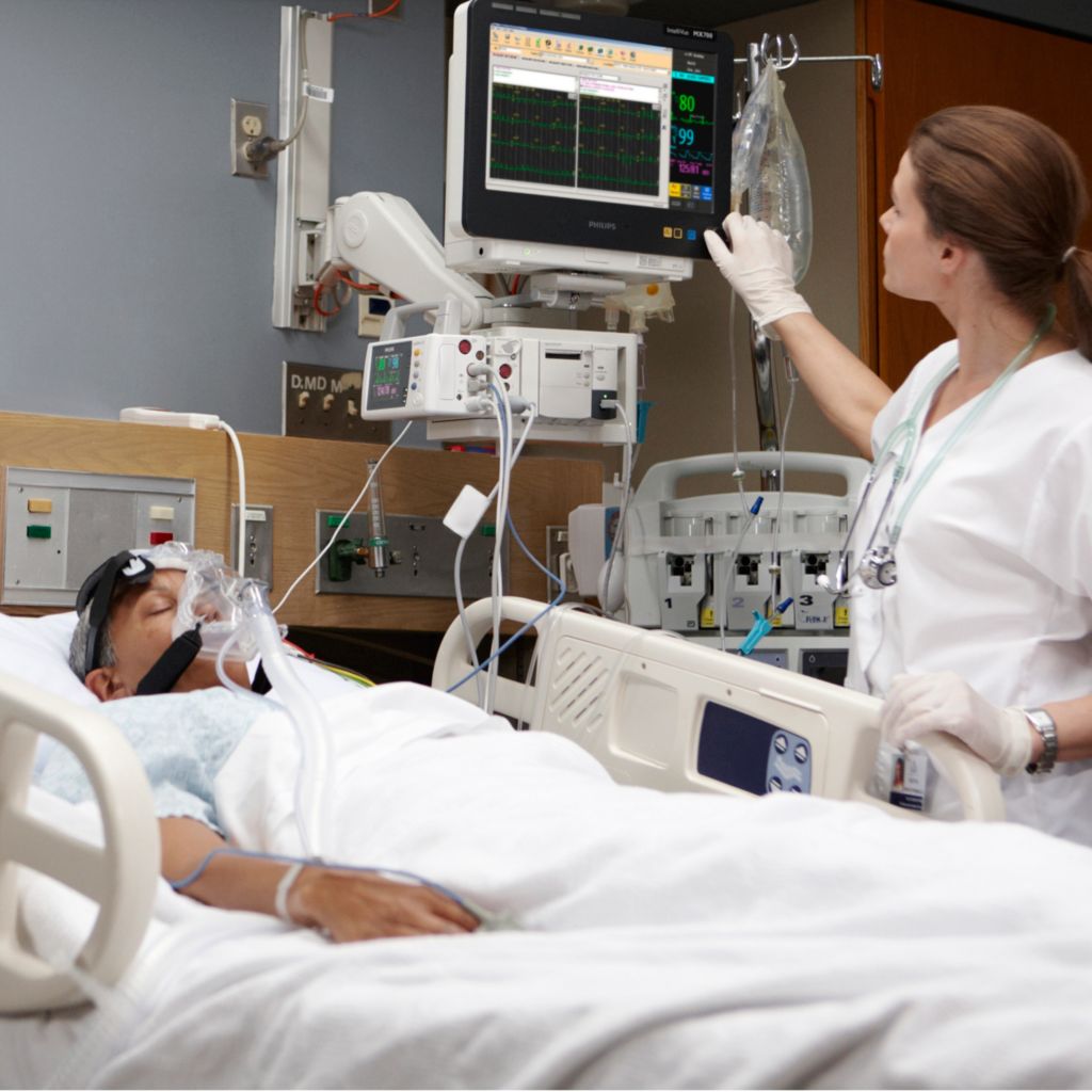clinician monitoring patient in hospital bed