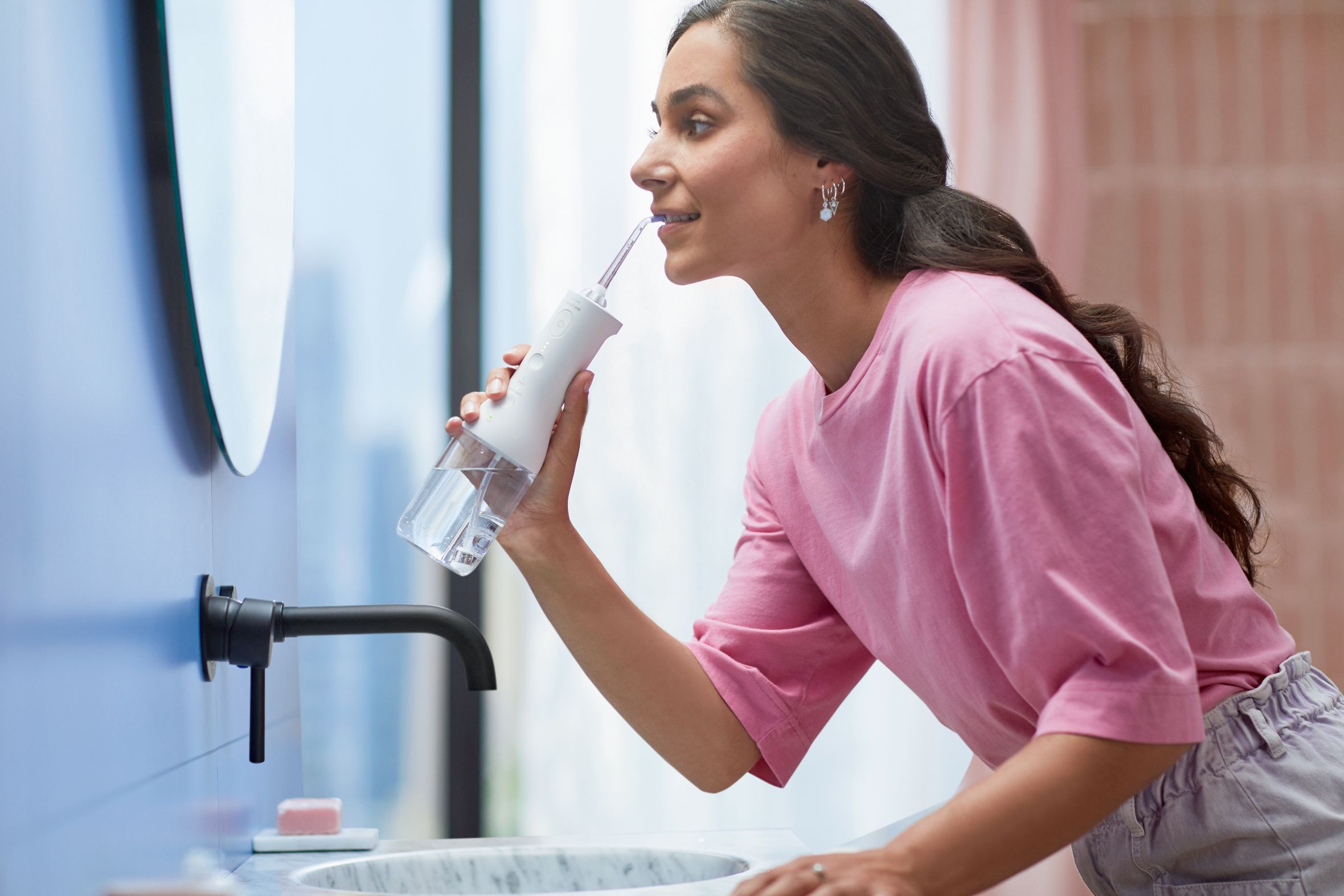 Una mujer cepill&aacute;ndose sus dientes blancos con un cepillo el&eacute;ctrico Philips Sonicare Airfloss.