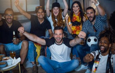 Group of football fans cheering together at home during a match
