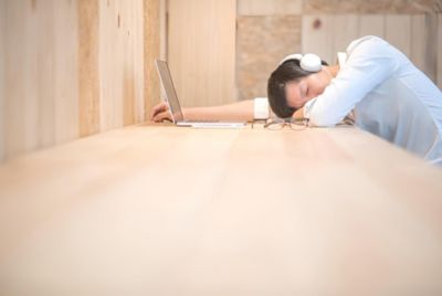 ヘッドフォンを付けて机で眠っている男性