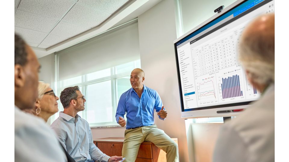 Healthcare leaders review and discuss ECG data and images on a large-format screen.