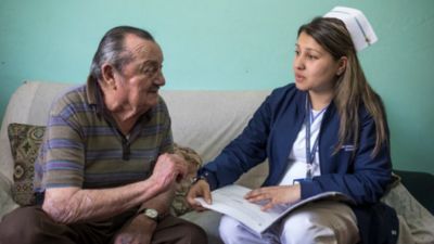 A nurse provides a primary care consultation to an elderly patient at home illustrating efforts by Philips Foundation to expand access to healthcare and improve early detection and management of chronic diseases in underserved communities across Latin America