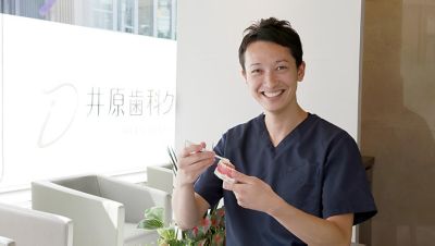 歯科モデルでブラッシングを実演しながら笑顔の歯科医