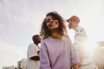 Grupo de jovens sorrindo ao ar livre em ambiente urbano com luz solar