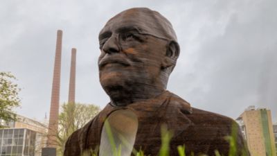 Bronzen beeld met schoorstenen in stadsgezicht