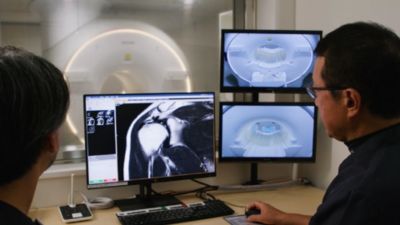Clinicians reviewing MRI images on workstation with Philips scanner in background