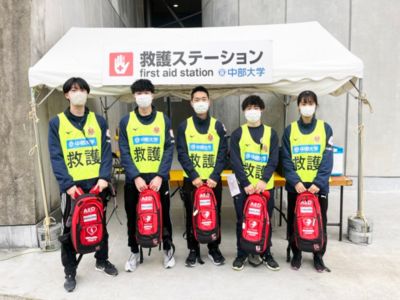 救急ステーションのテント前でフィリップスAEDパックを持った中部大学ボランティア