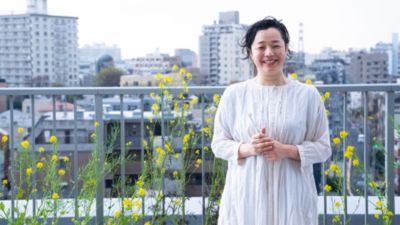 黄色い花が咲き誇る屋上庭園で白いドレスを着た笑顔の女性