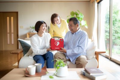 フィリップス HeartStart AEDを手にソファに座る家族