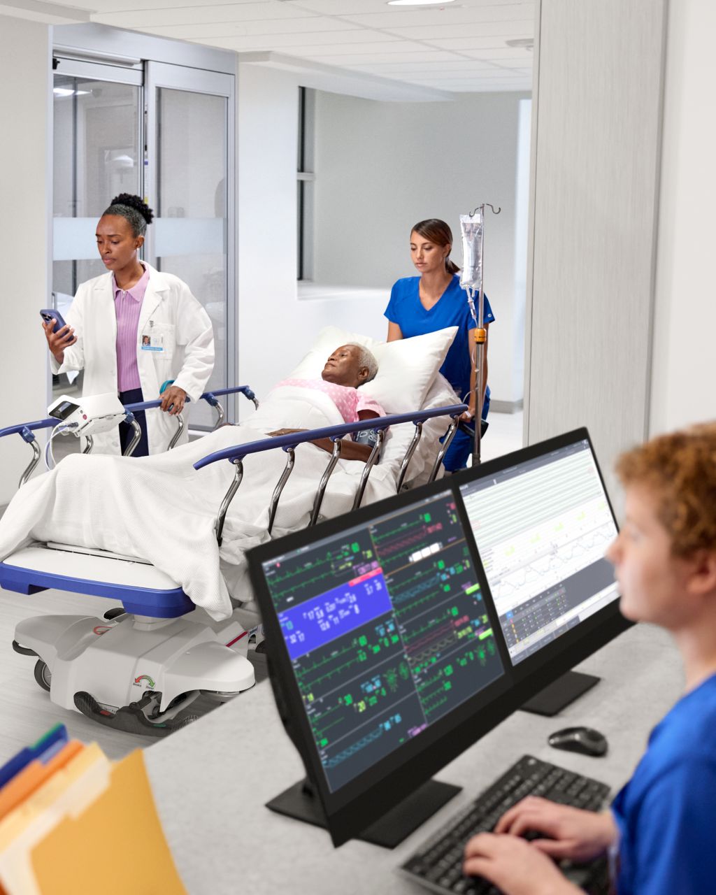 Pflegende an der Zentrale, während medizinisches Personal einen Patient auf einer Trage den Flur entlang schiebt.