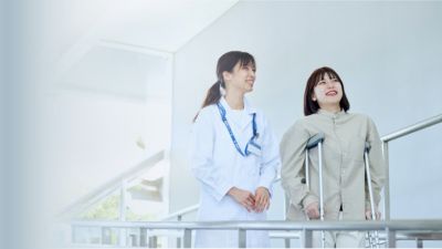医療従事者が松葉杖を使う患者を支えている