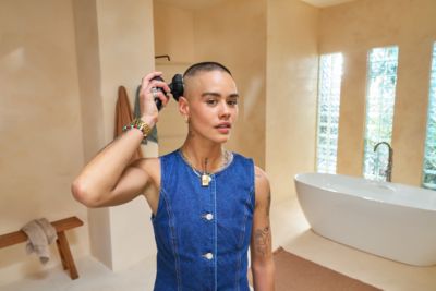 A female shaving head with Philips Norelco rotary head shaver in bathroom
