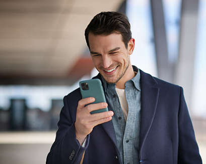 A man smiling while looking at his phone.
