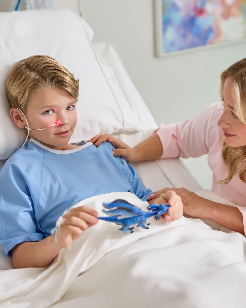 Patient pédiatrique portant le capteur de SpO₂ nasal Alar tout en tenant un dragon en peluche