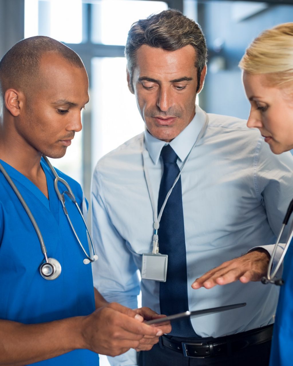Physicians and man in business clothes looking at tablet screen together