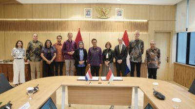 Kelompok berdiri di belakang dokumen yang telah ditandatangani di meja upacara MoU
