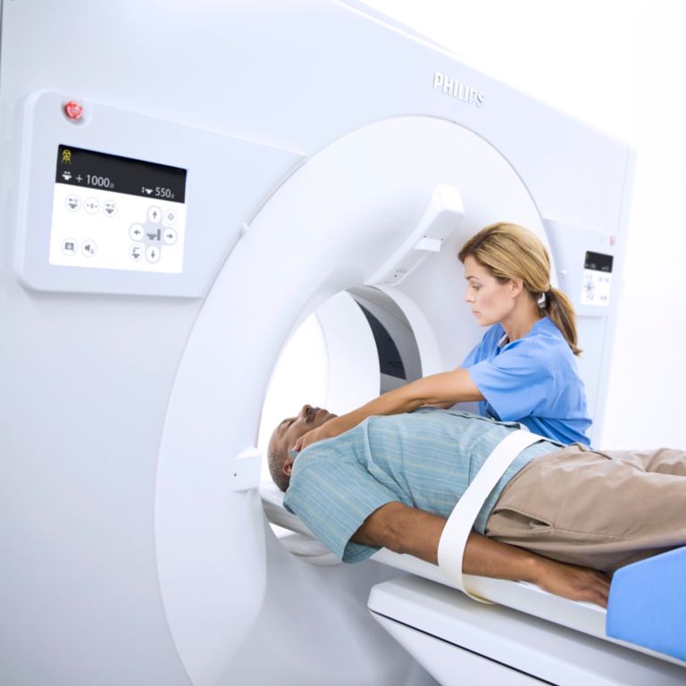 A technician prepares a patient for a CT scan