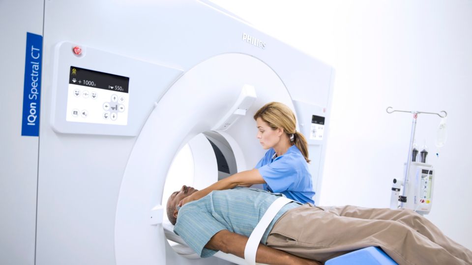 A technician prepares a patient for a CT scan