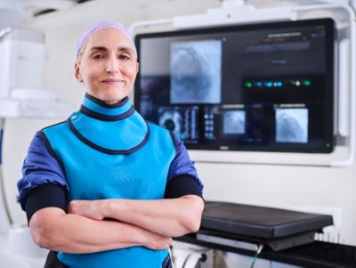 Clinician standing in interventional suite with imaging system in background